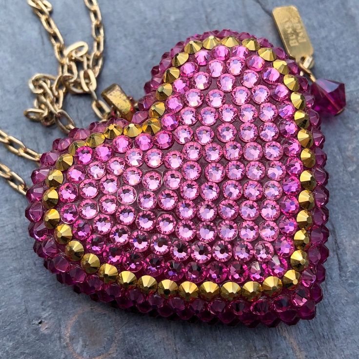 The Charmed pendant is a light and whimsical colorway, with over three hundred hand-placed crystals in shades of rose and a metallic gold halo in the center. DETAILS Heart Charm: 2” wide Chain: 18” chain + 2" extender Made to order. Please allow 1-2 weeks for delivery. SIZE CHART Rose Heart, Rosé Heart, Soft Rose, Gold Halo, Bright Gold, Pink Ombre, Rose Pink, Metallic Gold, Heart Charm