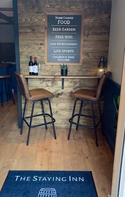 a bar with two stools in front of it and a sign that says the staying inn