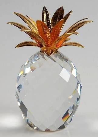 a golden pineapple on top of a clear crystal ball ornament with gold leaves