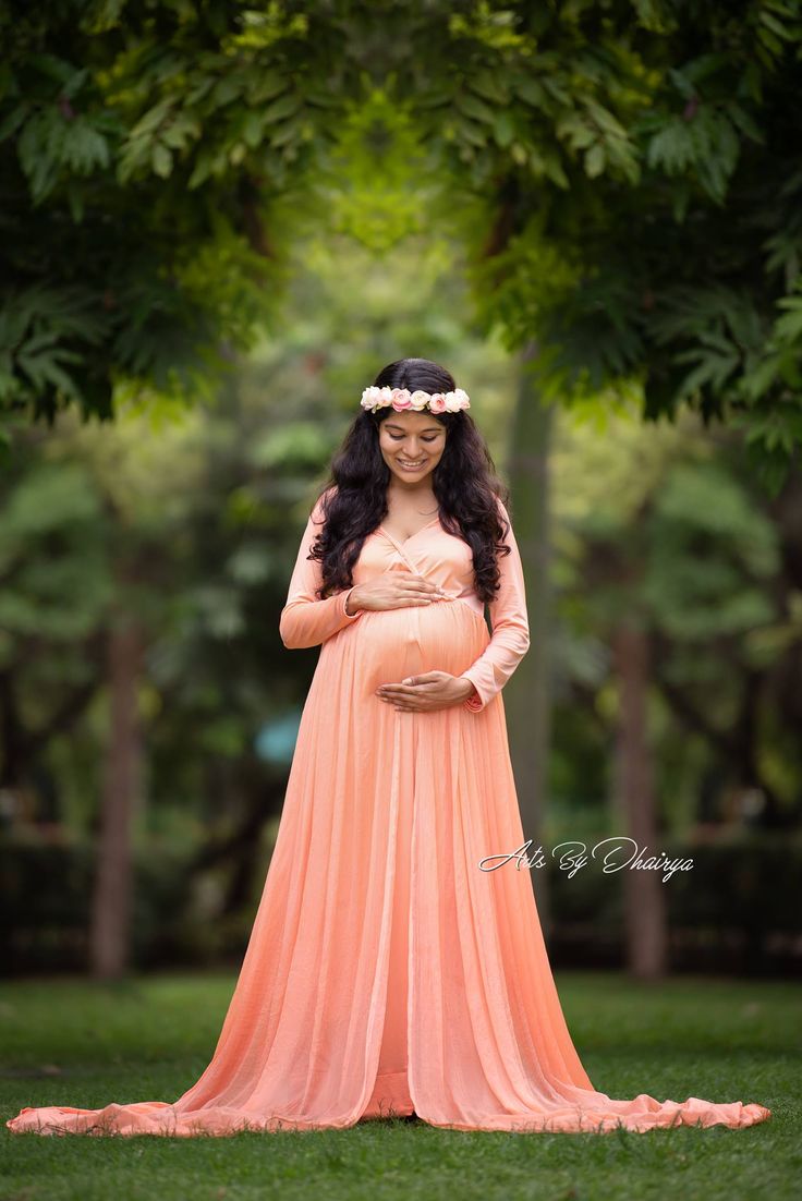 a pregnant woman in an orange dress poses for the camera with her hands on her belly