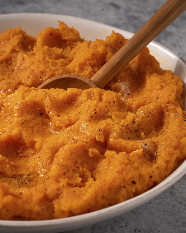 a white bowl filled with mashed sweet potatoes and a wooden spoon sitting in it