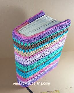 a multicolored crocheted basket sitting on top of a wooden stand next to a white wall