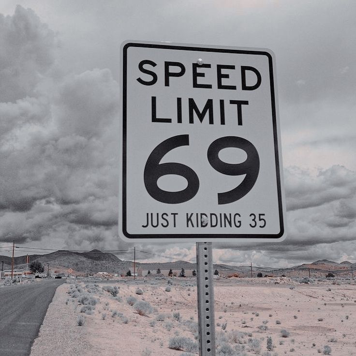 a speed limit sign sitting on the side of a road in the middle of nowhere