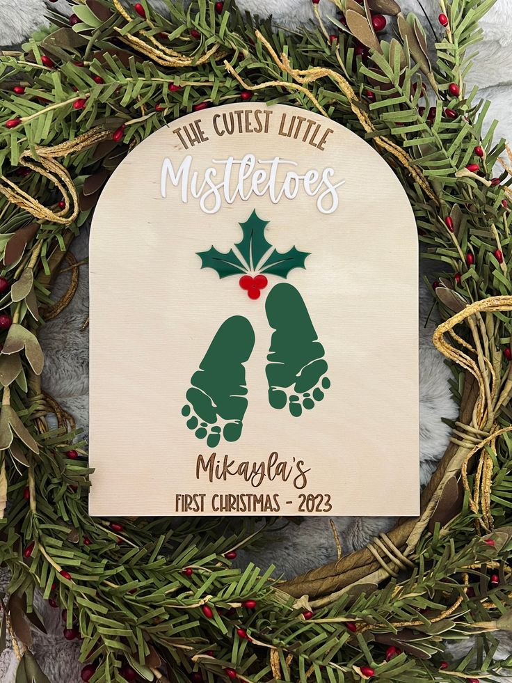 a christmas ornament hanging on a wreath with holly and mistlet leaves around it