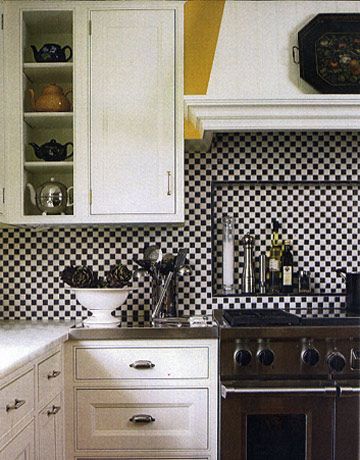 a kitchen with white cabinets and black and white checkerboard backsplashing