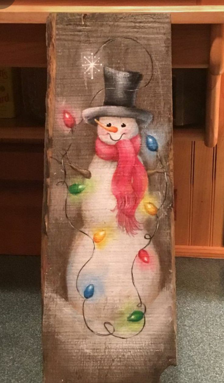 a wooden sign with a snowman painted on it