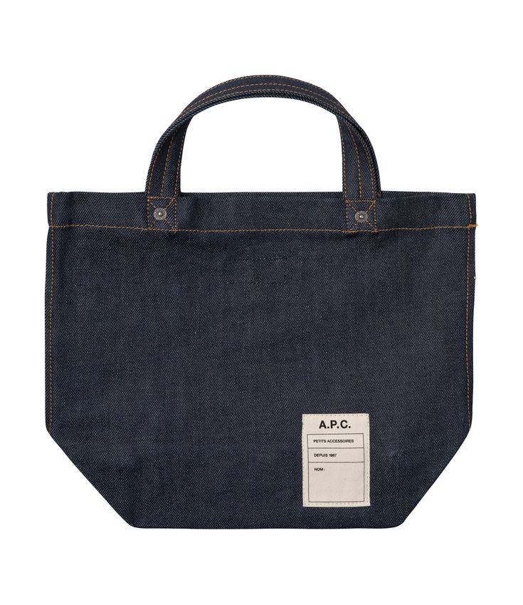 A.P.C. tote bag. - Unisex model. - Two large handles. May be carried by hand or on shoulder. - Exterior pocket embroidered with caramel-colored A.P.C. logo. - Interior pocket. - Rivets engraved A.P.C. - Caramel-colored topstitching. Faux Leather Bag, Indigo Denim, Exclusive Clothing, C Logo, Mini Tote Bag, Backpack Tote Bag, Caramel Color, Scarf Jewelry, Mini Tote