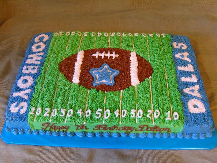 a birthday cake with a football on the field and stars in blue, green, and white frosting