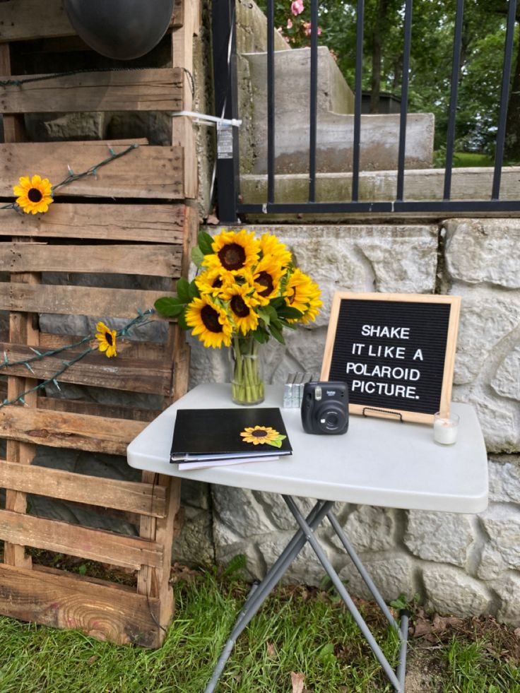 a small table with flowers and a sign on it