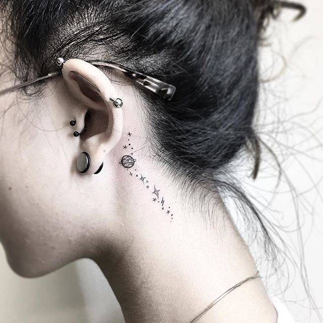 a woman's ear has a small flower tattoo on her left side behind the ear