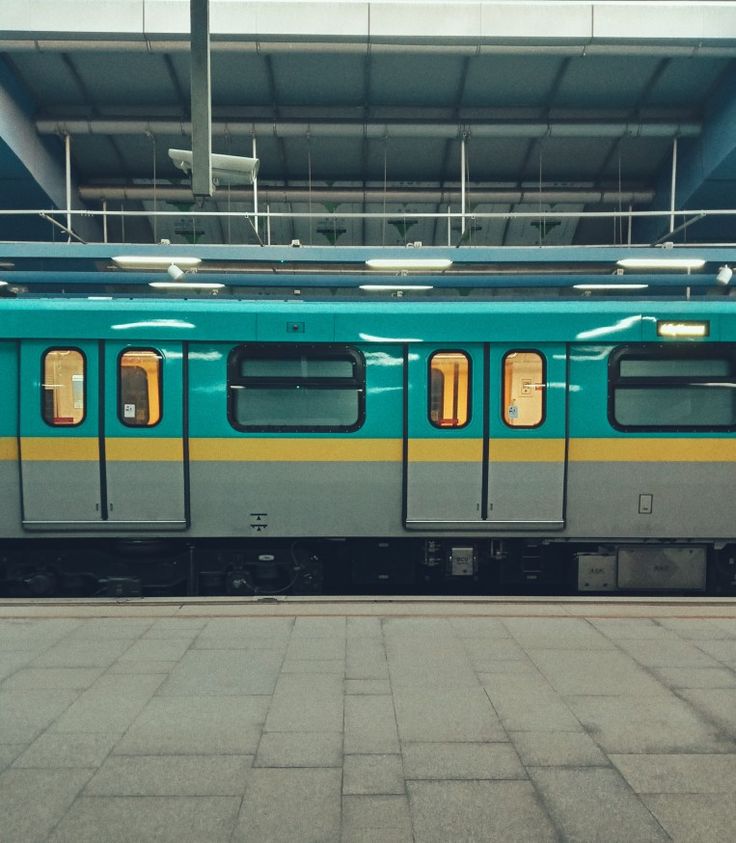 a green train is parked at the station