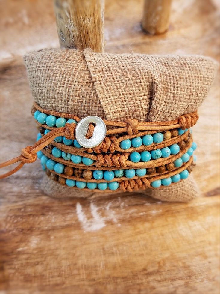 Chic boho wrap bracelet with Bright Turquoise colored beads mixed with Picture Jasper with decorative snake knot accents. Threaded onto natural color raw tan leather. Wraps around the wrist 5 times total. Bracelets are approximately 37 inches in length total and adjustable between 34-36 inches due to several loop closu Adjustable Turquoise Bohemian Wrap Bracelet, Adjustable Bohemian Turquoise Wrap Bracelet, Adjustable Hand Wrapped Leather Wrap Bracelet, Adjustable Leather Bracelets With Natural Stones, Bohemian Hand Wrapped Beaded Bracelets On Waxed Cord, Brown Hand Wrapped Beaded Bracelets For Festivals, Rustic Adjustable Turquoise Beaded Bracelets, Hand Wrapped Brown Beaded Bracelets For Festivals, Bohemian Adjustable Hand Wrapped Leather Bracelet