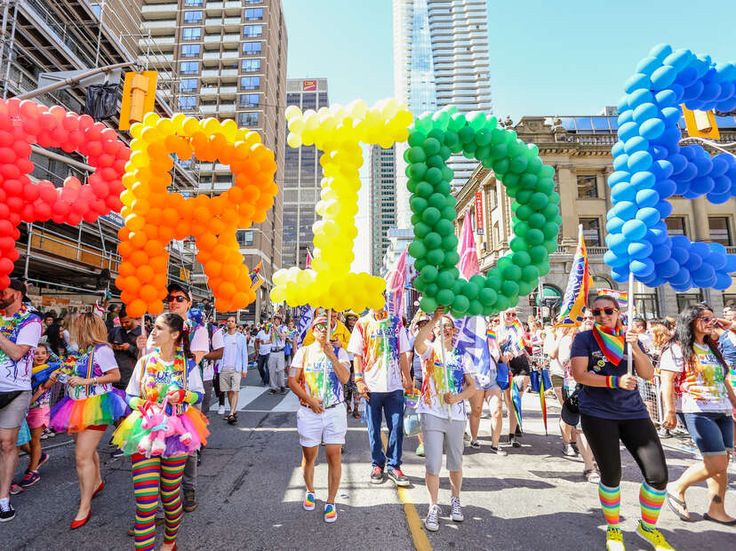 people are walking down the street with balloons in the shape of letters that spell pride