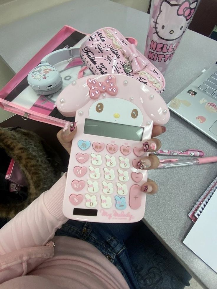 a person holding a pink calculator with hello kitty on it