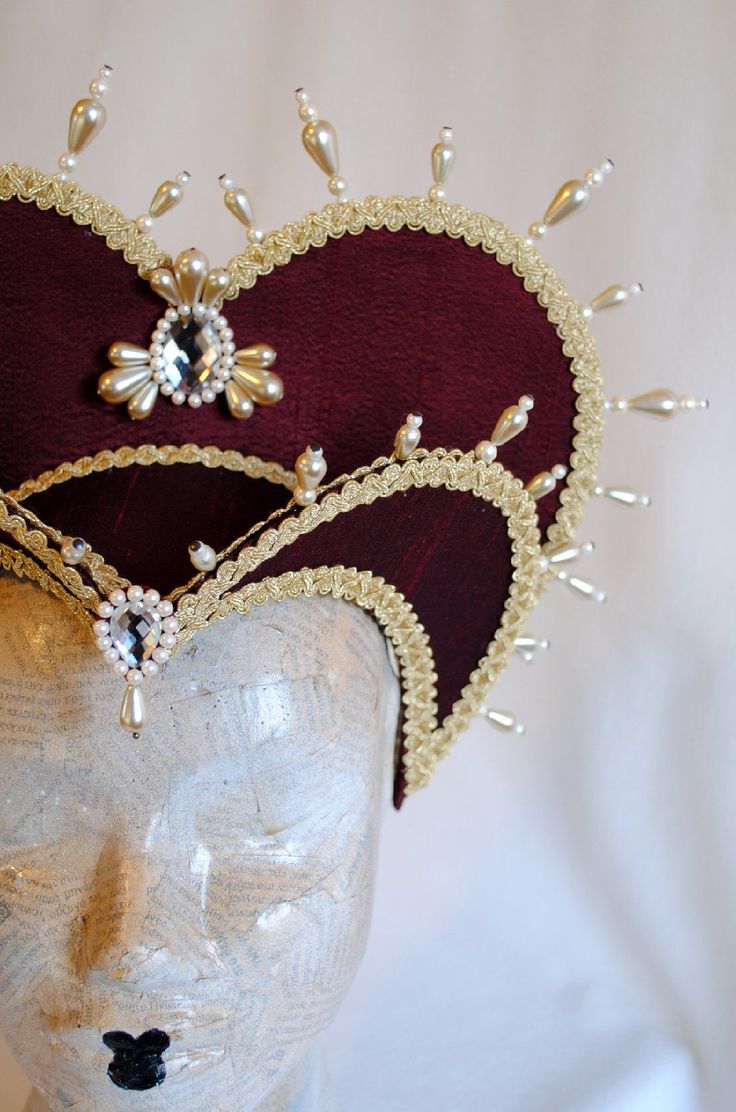 This royal Tudor inspired attifet headdress is covered with silk shantung in your choice of color.Either a rich burgundy or black.It is embellished with golden cord trimming all around the edges.It is further trimmed with pearl bead details that create a halo effect. The piece is completed with clear crystal and pearl handmade elements placed at the center of both at the frond as well as the back part,to add that extra drama that we all love! The base is a headband style, completely handmade to Elizabethan Costume, Halo Effect, Burgundy And Gold, Headband Styles, Costume Hats, Headdress, Love Is All, Pearl Beads, Costume Accessories