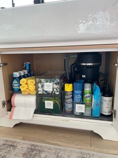 the inside of a kitchen cabinet filled with cleaning products and toiletries, including hand towels