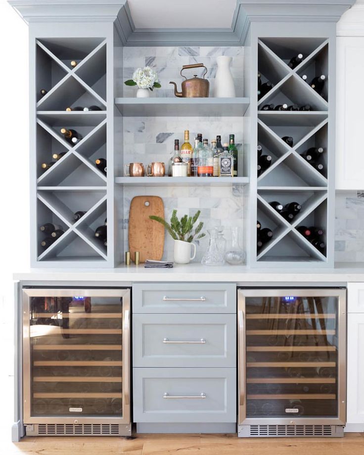 a kitchen with white cabinets and wine racks on the wall above it is an empty wooden floor