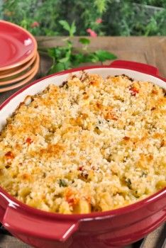 a red casserole dish filled with macaroni and cheese on a wooden table