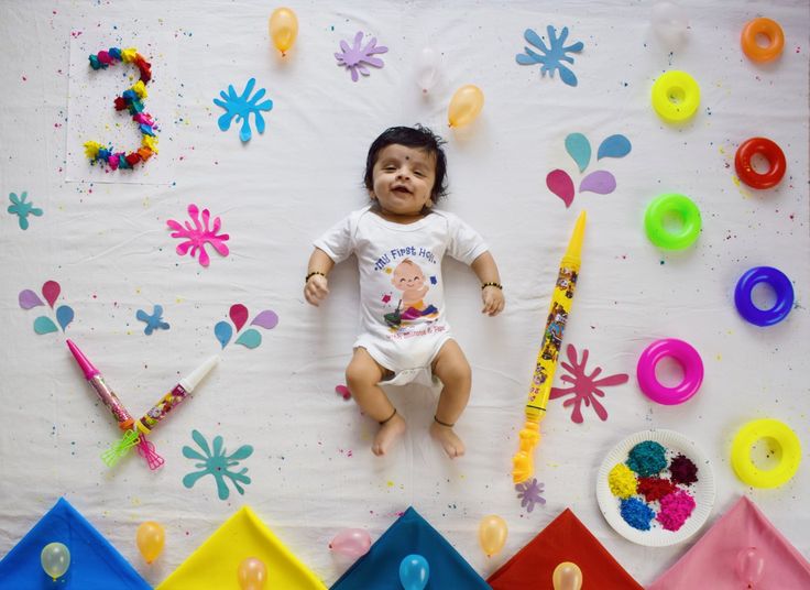 a baby is laying on the floor surrounded by balloons and confetti, such as crayons