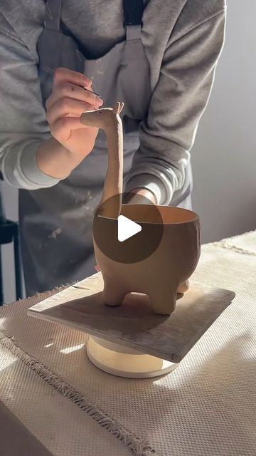 a woman is making an elephant sculpture out of clay