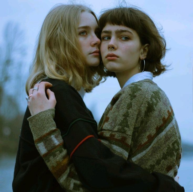 two women embracing each other in front of water