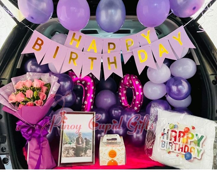 a birthday party with balloons, flowers and gifts in the back of a car trunk