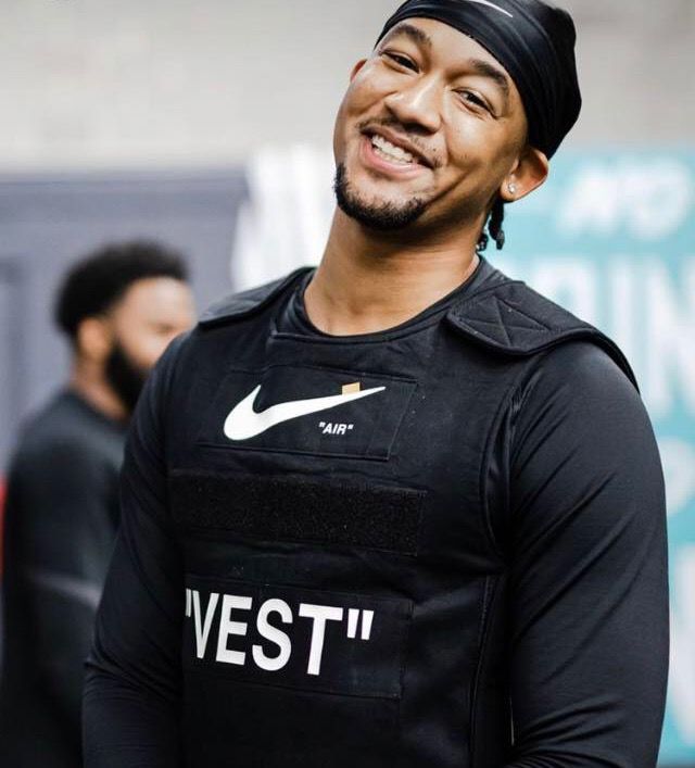 a man wearing a nike vest and headband smiles while standing in front of other men