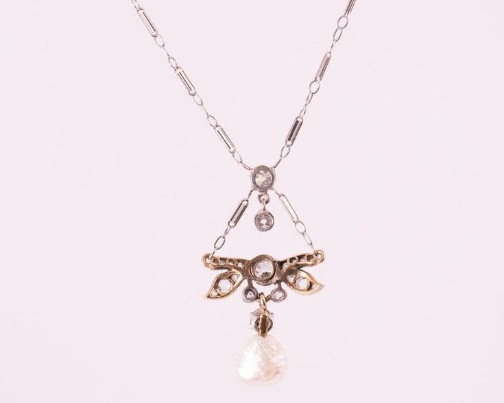 Item Description: This 1870s Victorian Dragonfly motif Necklace features a Natural Free Form Pearl and Old Mine Diamonds in 14 Karat White Gold and Platinum. A Diamond Dragonfly charm drops from the chain and suspends a diamond and pearl charm. The Natural Pearl measures approximately 7.5 millimeters and is Iridescent White with pinks and blues. It has natural rippling and dimpling. This delicate necklace measures 16 inches long and has a safety clasp for extra security. This piece shows that hi Dragonfly Motif, Iridescent White, Dragonfly Charm, Dragonfly Necklace, Natural Pearl, Pearl Charms, Delicate Necklace, Natural Pearls, Antique Victorian