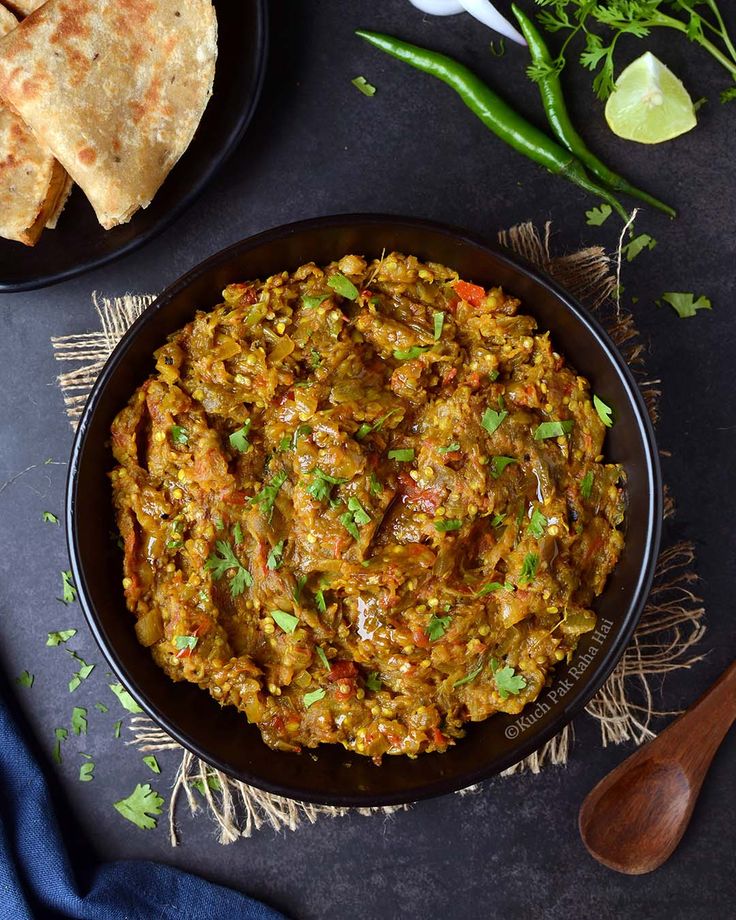 a black bowl filled with food next to some pita bread