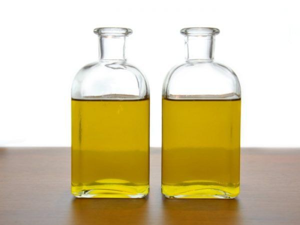 two bottles filled with oil sitting on top of a wooden table