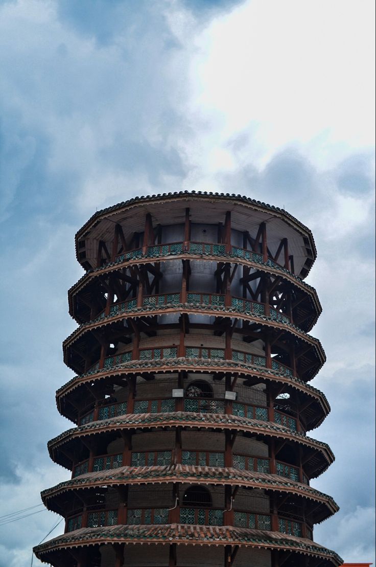 a very tall tower with a clock on it's side in front of a cloudy sky