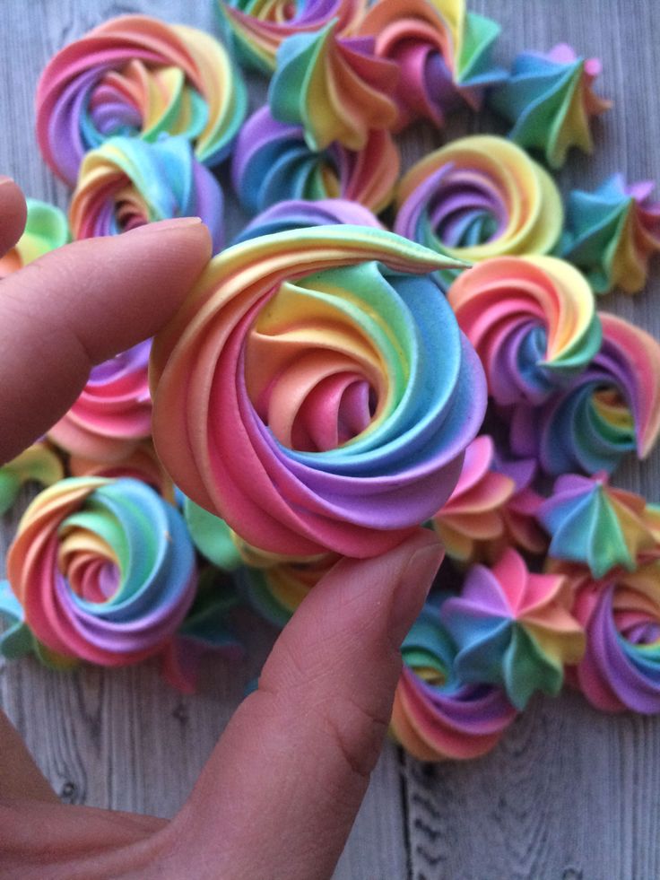 someone is holding some colorful paper flowers on a wooden table and it looks like they have been rolled together