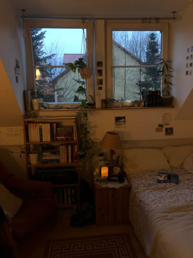 a bed room with a neatly made bed next to two windows and a book shelf