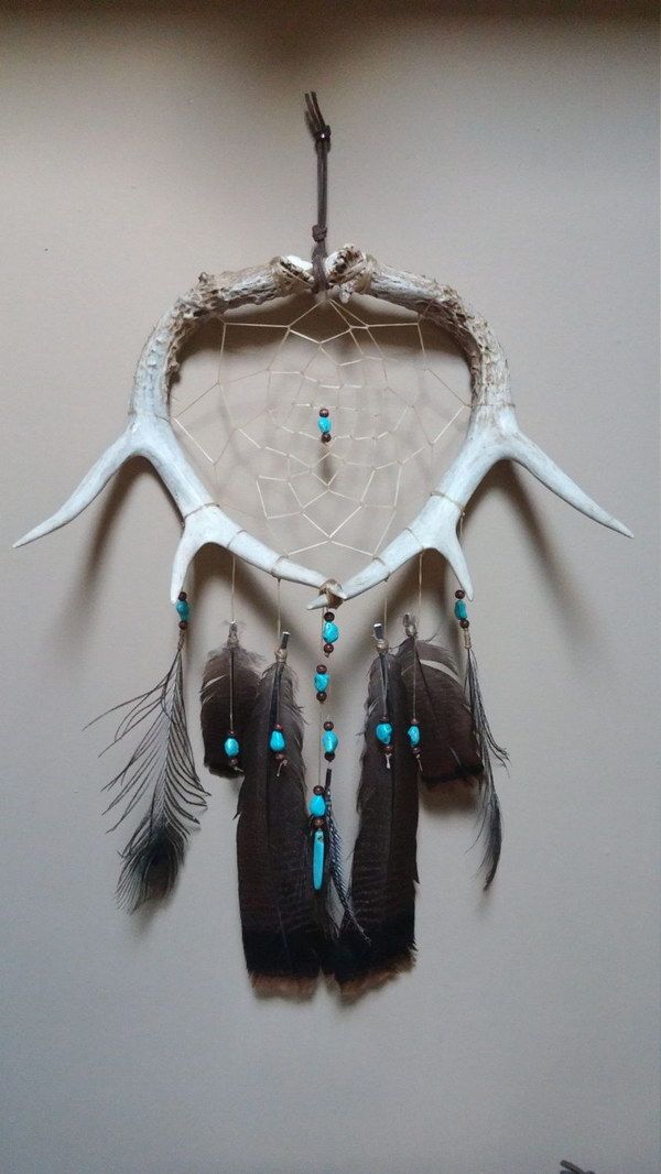 a dream catcher with antlers and feathers hanging on the wall