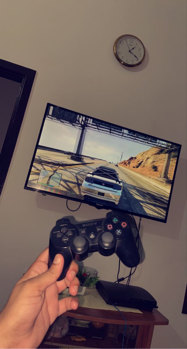 a person holding a video game controller in front of a tv with a car on it