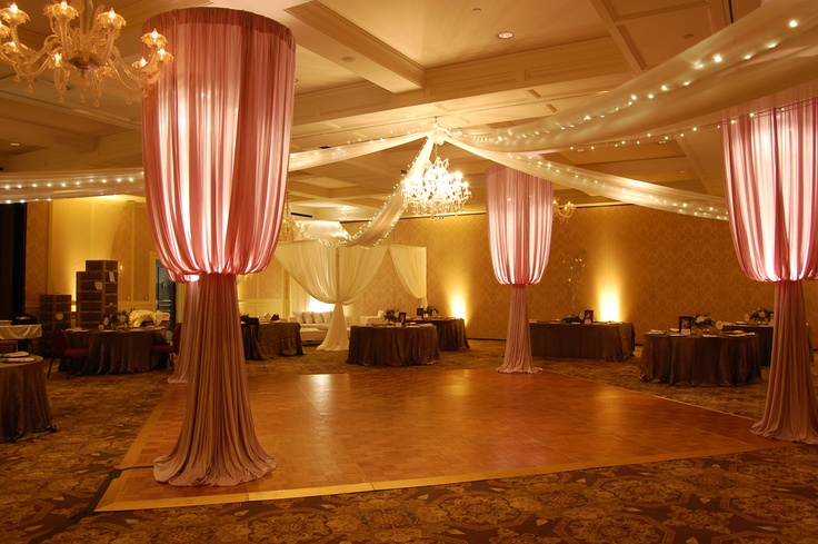 an empty ballroom with chandeliers and draping on the ceiling is lit by lights