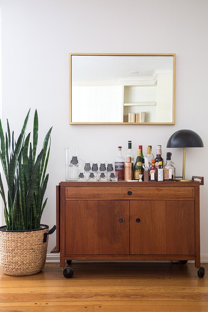 a wooden cabinet sitting next to a potted plant on top of a hard wood floor