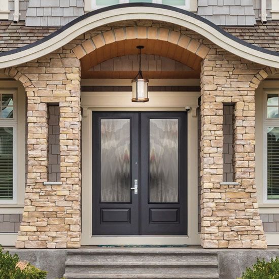 the front entrance to a house with two double doors and brick pillars on either side