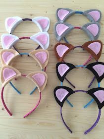 four cat ears are lined up on a wooden surface, each with different colors and sizes