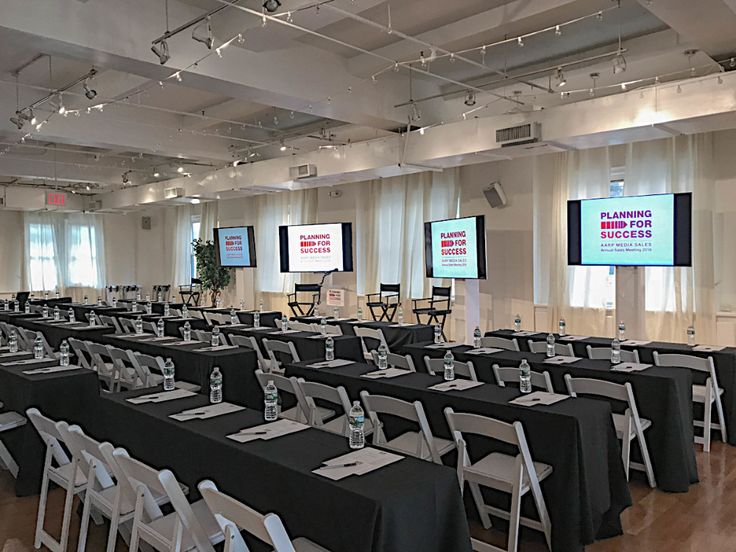 an empty conference room is set up with black tables and white folding chairs for people to sit at