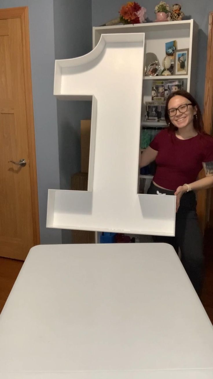 a woman standing in front of a large letter