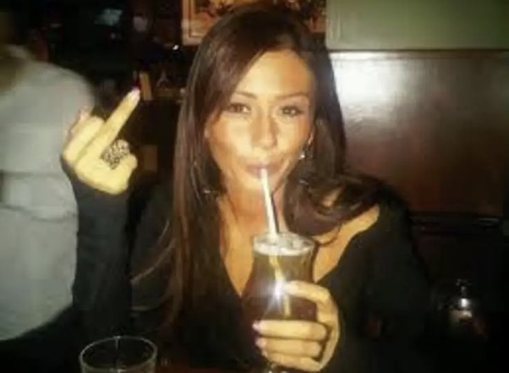 a woman holding a drink in her right hand and making the peace sign with her fingers