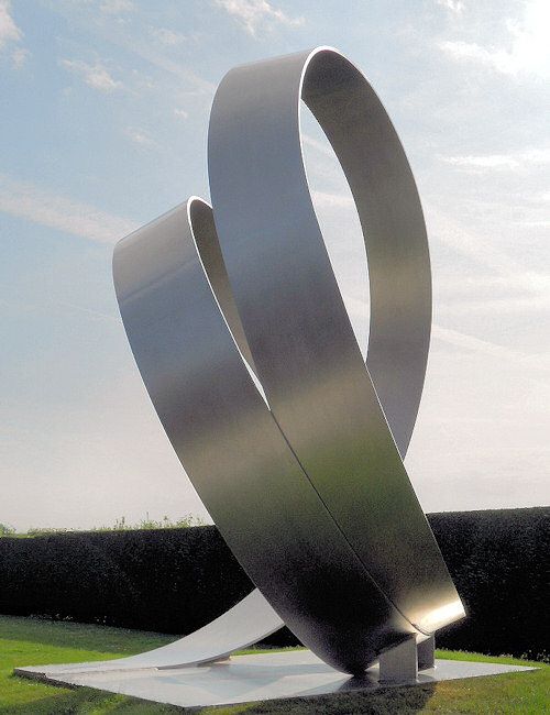 a large metal sculpture sitting on top of a lush green field