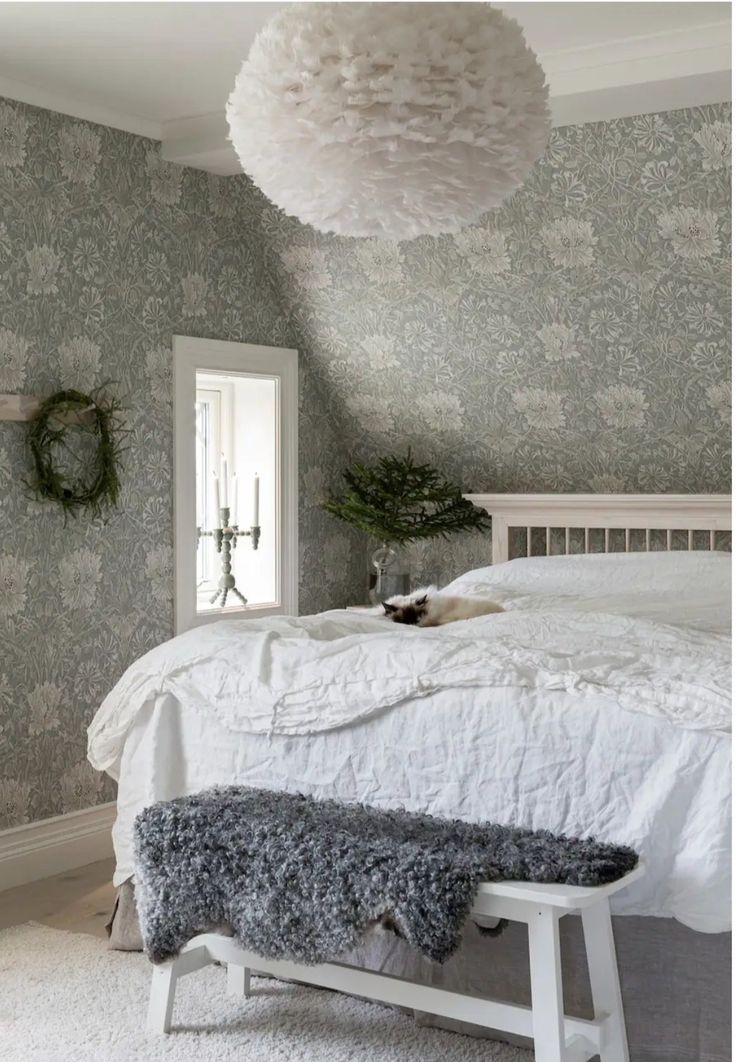 a white bed sitting in a bedroom next to a wallpapered ceiling and window