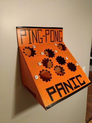 an orange cardboard box with black letters and gears attached to the side, hanging on a wall