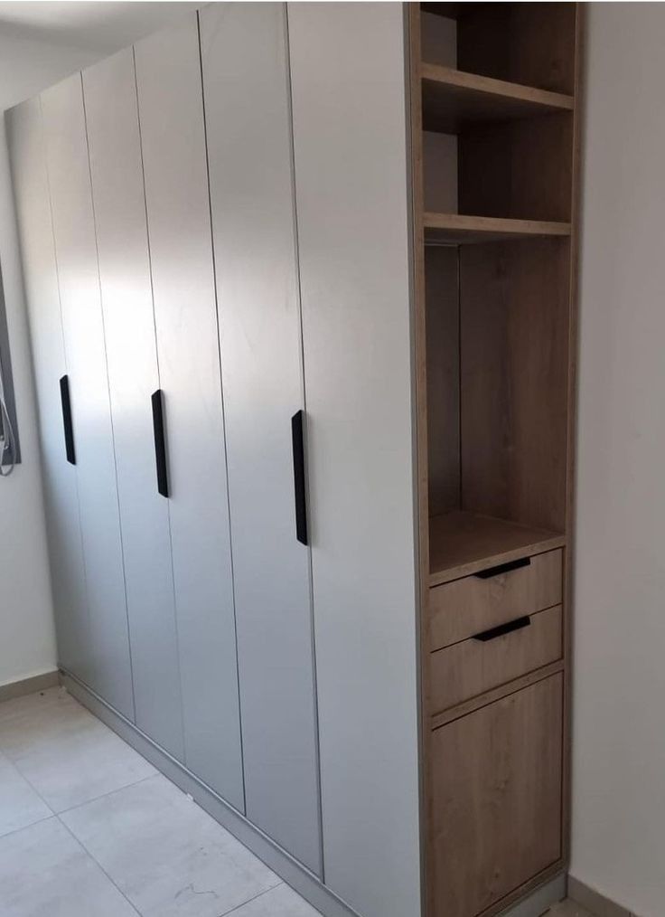 an empty room with white cupboards and black handles