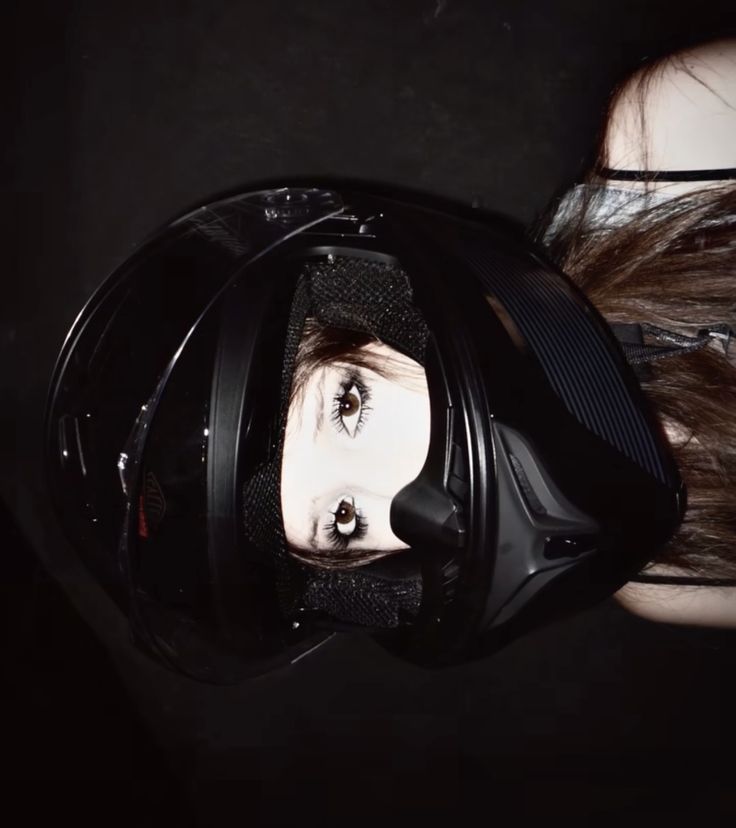 a woman wearing a motorcycle helmet with her face reflected in the mirror