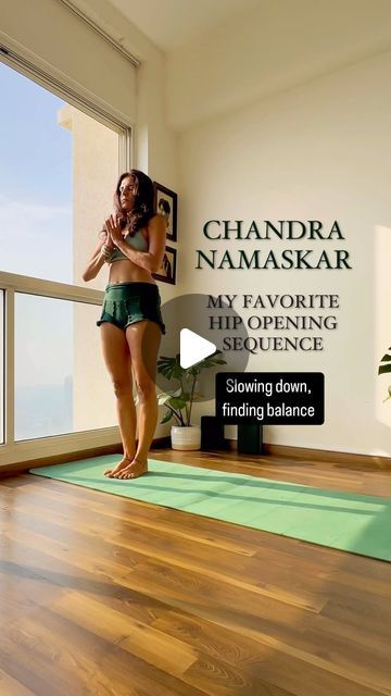 a woman standing in front of a window on top of a wooden floor next to a green rug