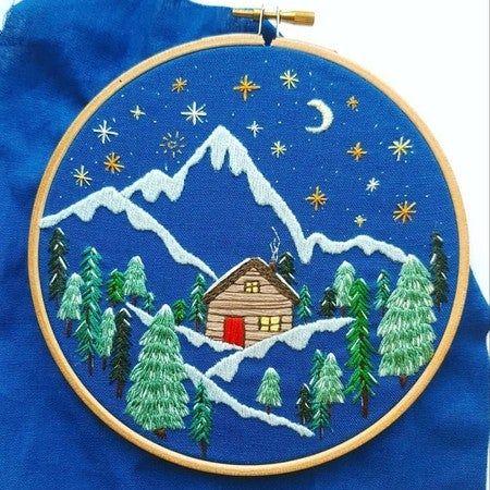 a blue bag with a small cabin in the woods on it's front pocket