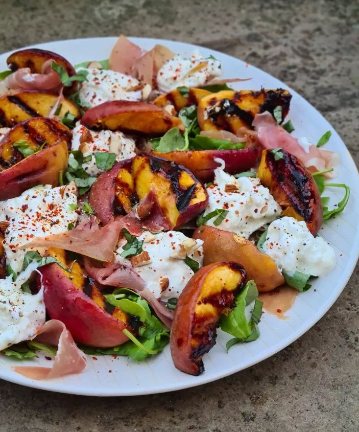 a white plate topped with grilled peaches, feta cheese and lettuce